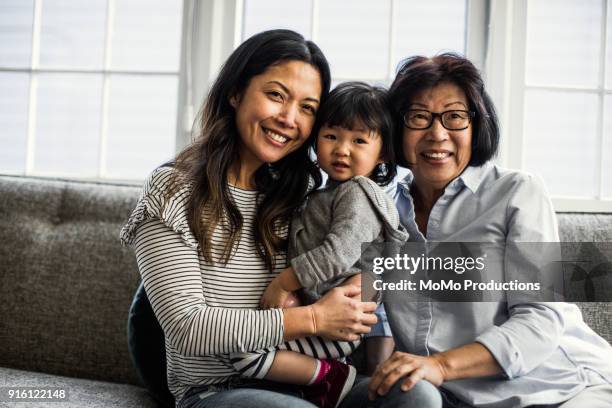 grandmother, daughter and granddaughter on couch at home - beautiful chinese girls stock pictures, royalty-free photos & images