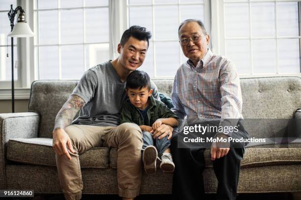 grandfather, son and grandson on couch at home - beige pants - fotografias e filmes do acervo