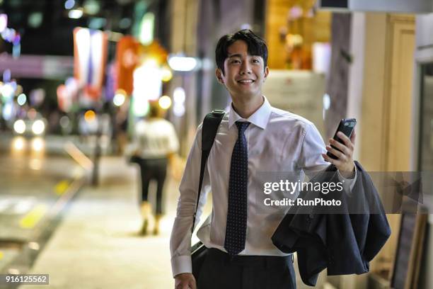 smiling businessman with cell phone looking away - night suit stock pictures, royalty-free photos & images