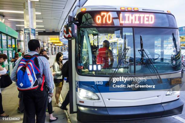 Men and women boarding a Q70 Limited bus outside LaGuardia Airport.