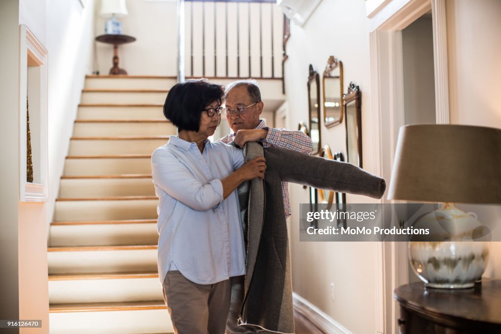 Senior man helping wife with coat