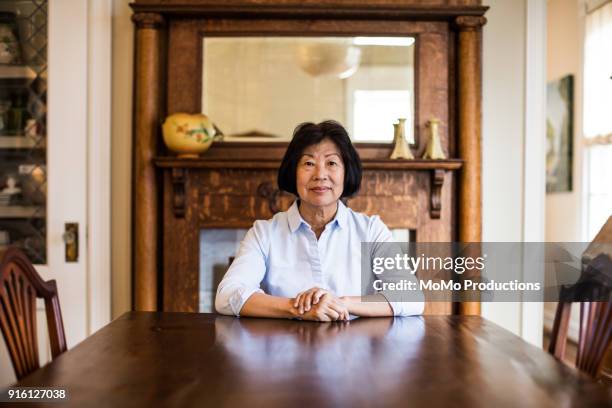 portrait of senior woman at home - sitting at table looking at camera stock-fotos und bilder