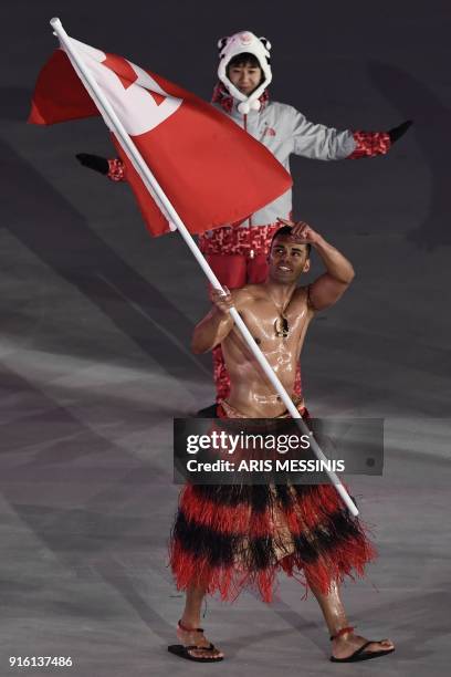 Tonga's flagbearer Pita Taufatofua leads his country's delegation as he parades in shirtless traditional attire better suited for the tropics during...