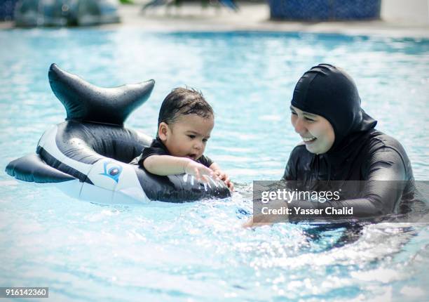 mother an baby boy in inflatable on swimming pool - burkini bildbanksfoton och bilder