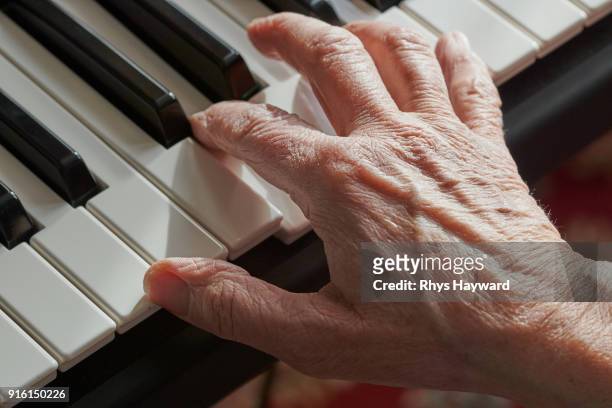 macro senior hand playing piano keyboard - keyboard player fotografías e imágenes de stock