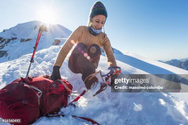 woman hiker wearing crampons on mountain boots - crampon stockfoto's en -beelden