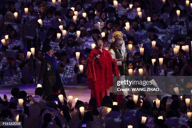 Singers Ha Hyun-woo, Lee Eun-mi, Jeon In-kwon and An Ji-yeong perform onstage surrounded by people holding candles during the opening ceremony of the...