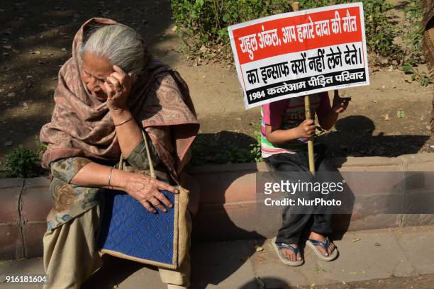 Young protestor sits holding a placard demanding justice from Indian National Congress Party President Rahul Gandhi along Akbar Road in New Delhi on...
