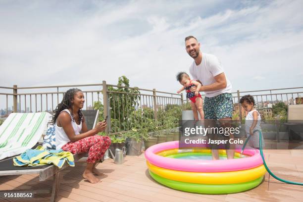 parents playing with children in inflatable swimming pool - two kids playing with hose stock pictures, royalty-free photos & images