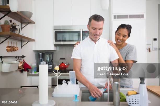 woman watching man washing baby bottle - husband cleaning stock pictures, royalty-free photos & images