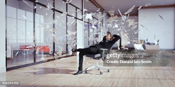 businessman relaxing chair surrounded by shards of glass - freeze motion stock-fotos und bilder