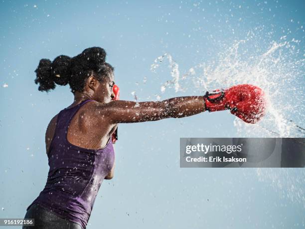 water spraying on black woman boxing - steinschlag stock-fotos und bilder