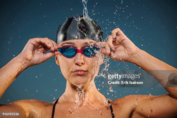 water splashing on caucasian woman adjusting swimming goggles - studio portrait swimmer photos et images de collection