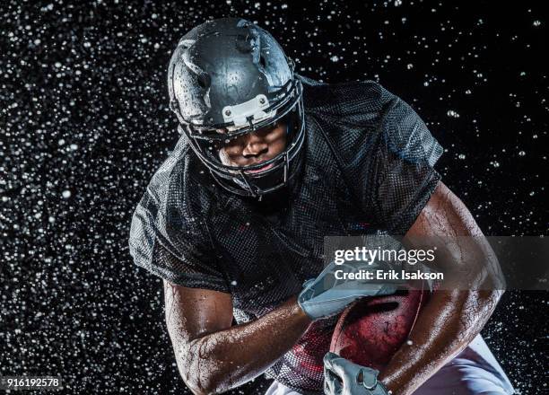 water splashing on black football player - american football player studio stock pictures, royalty-free photos & images