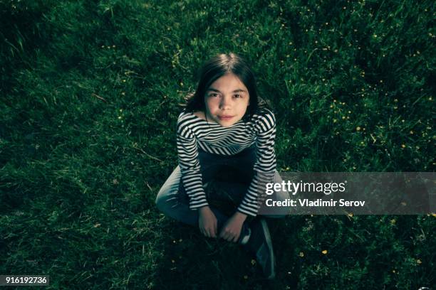 smiling caucasian teenage girl sitting in grass - one teenage girl only ストックフォトと画像