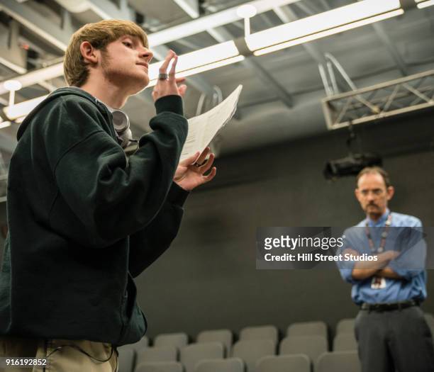 teacher listening to student reading script - man standing and gesturing stock-fotos und bilder