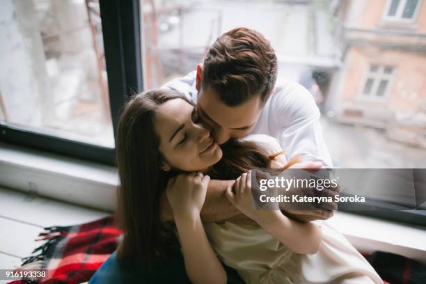 caucasian couple hugging on bench near window - coppia passione foto e immagini stock