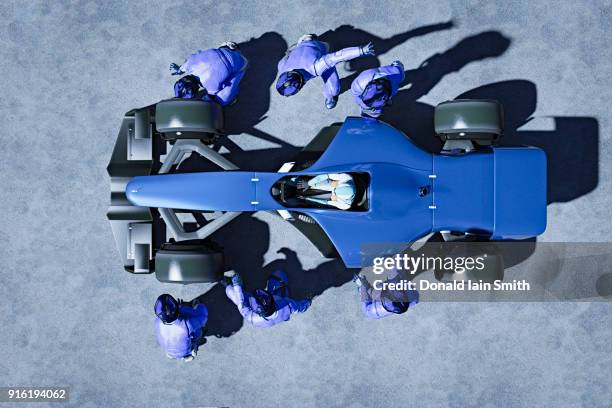 futuristic pit crew servicing race car - sports car photos et images de collection