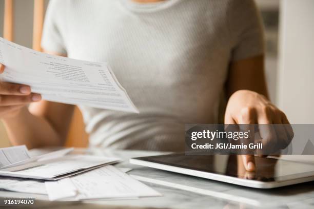 african american woman paying bills with digital tablet - invoice stock-fotos und bilder