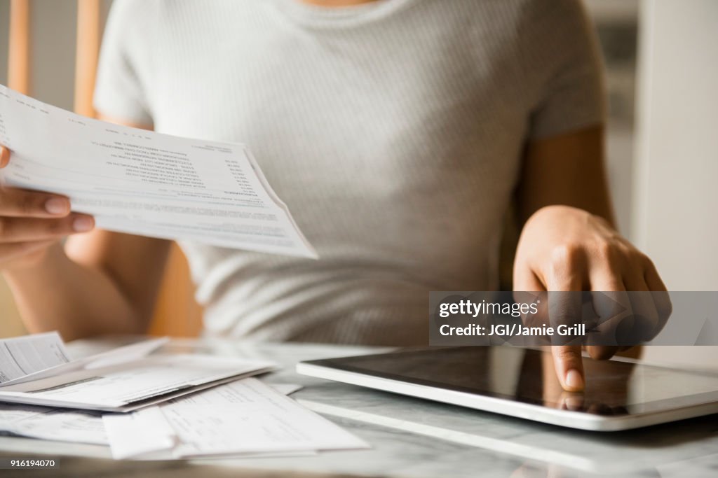 African American woman paying bills with digital tablet