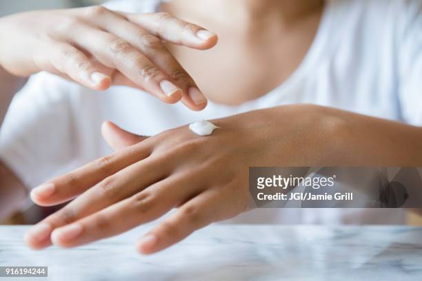 african american woman applying lotion to hand - hydraterende creme stockfoto's en -beelden