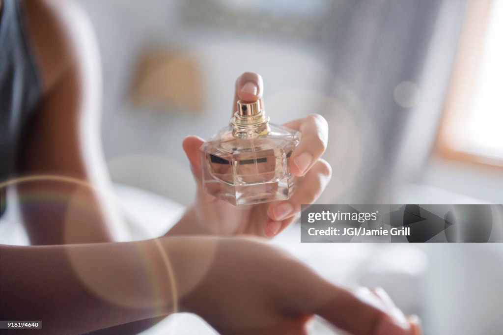 African American woman spraying perfume on wrist