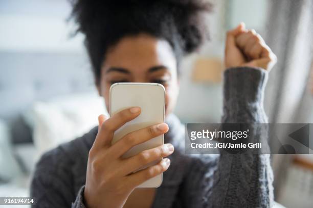 african american woman celebrating while texting on cell phone - viso nascosto foto e immagini stock