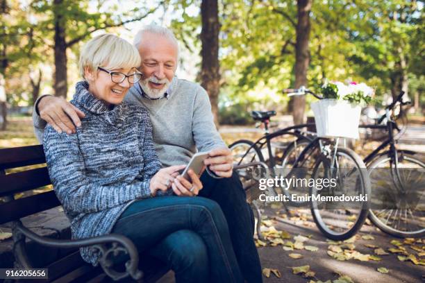 senior pareja con teléfono inteligente al aire libre - action laptop fotografías e imágenes de stock
