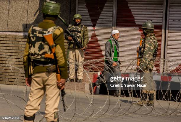 Kashmiri Muslim walk amid a group of Indian government forces as Indian government forces stand guard in the Old City during restrictions on the...