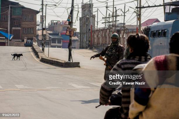 An Indian paramilitary trooper stops a Kashmiri scooterist on a deserted road, in front Kashmir's Jamia Masjid in the Old City during restrictions on...