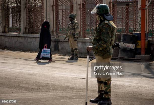 Kashmiri Muslim woman negotiates restrictions as Indian paramilitary troopers stand guard in the Old City during restrictions on the fifth death...