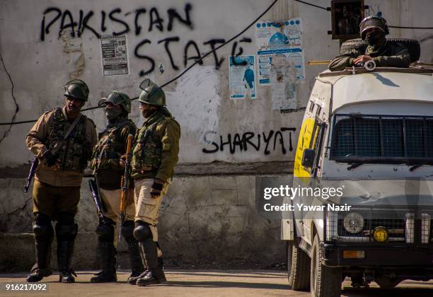 Indian government forces stand guard, in front the graffiti written by Kashmiri Muslim protesters on a house, in the Old City during restrictions on...