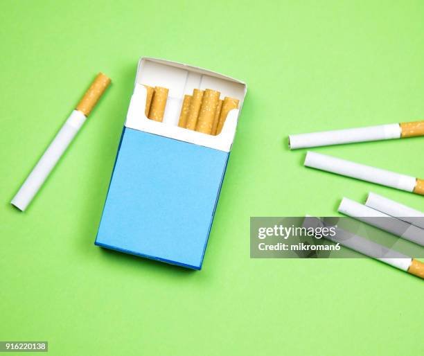 cigarette box and cigarettes on green background - zigarettenfilter stock-fotos und bilder