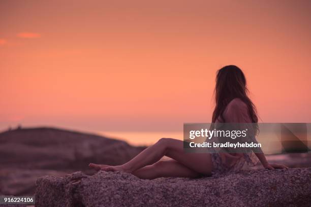 asian woman enjoying sunset in camps bay, south africa - camps bay stock pictures, royalty-free photos & images