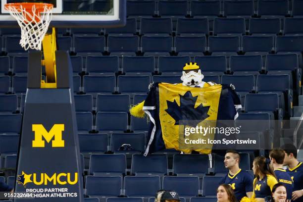 Fan dressed in a Michigan-theme Star Wars stormtrooper costume holds a Michigan-themed Canadian flag during a regular season Big 10 Conference...