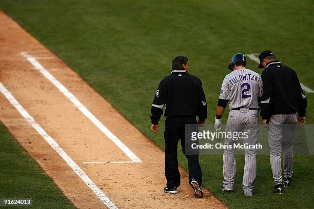 Troy Tulowitzki of the Colorado Rockies walks towards first base flanked by manager Jim Tracy and trainer Keith Dugger after Tulowitzki was hit by a...