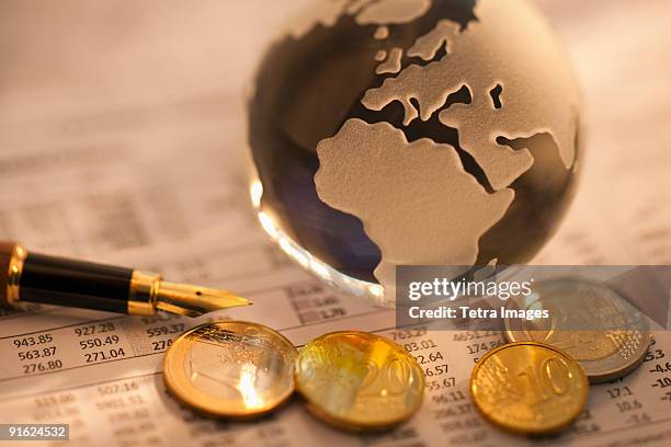 a globe on business papers with some coins - all the money in the world stock-fotos und bilder
