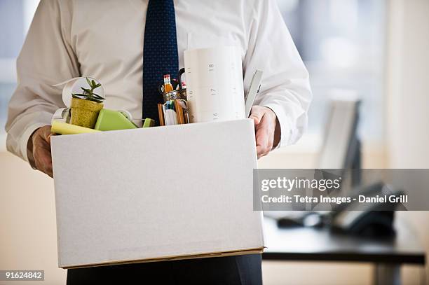 a businessman with a box full of desk stuff - unemployment stock-fotos und bilder