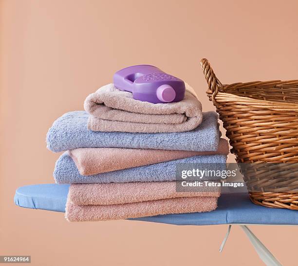 an ironing board with towels and detergent - folded towels stock pictures, royalty-free photos & images