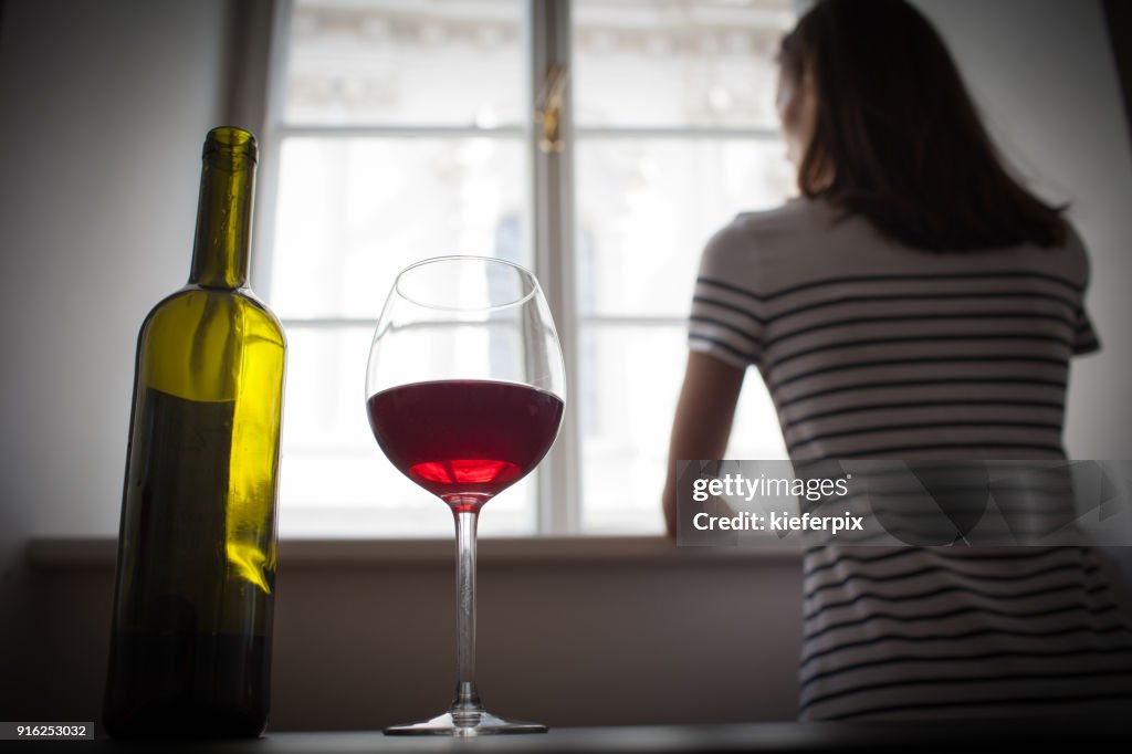 Woman drinking wine alone in the dark room
