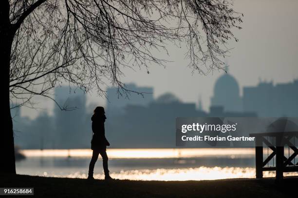 Woman walks along the Havel river in front of the cityscape of Potsdam during sunset on February 09, 2018 in Berlin, Germany.