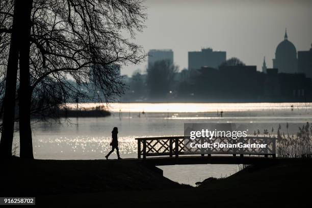 Woman walks along the Havel river in front of the cityscape of Potsdam during sunset on February 09, 2018 in Berlin, Germany.