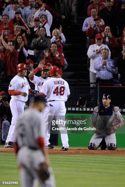 Torii Hunter of the Los Angeles Angels of Anaheim celebrates with teammates after hitting a three-run home run as starting pitcher Jon Lester and...