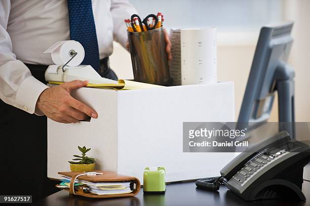 a businessman packing up desk - downsizing unemployment stock-fotos und bilder