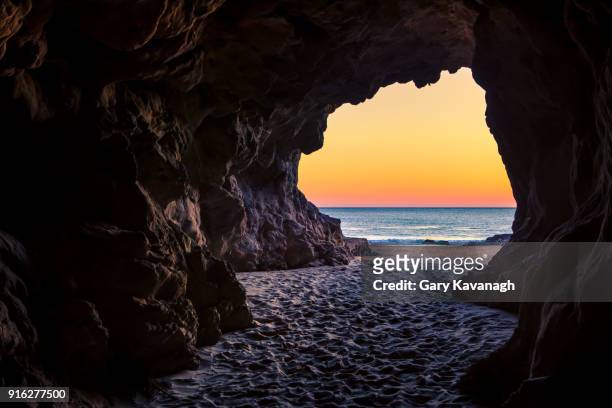 looking out of a beach cave at sunset, leo carillo state beach, california - cave stock pictures, royalty-free photos & images