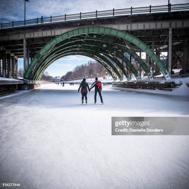 skaters holding hands and skating under a bridge on the rideau canal for winterlude - danielle donders stock pictures, royalty-free photos & images