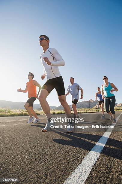 runners on a road - sportsman stock pictures, royalty-free photos & images
