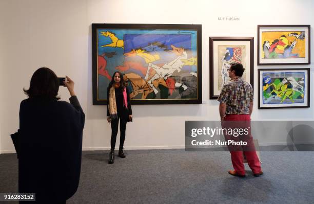 Spectators take photos in front of paintings by famous artist M. F. Husain at the India Art Fair 2018 held on the Okhla NSIC grounds in New Delhi on...