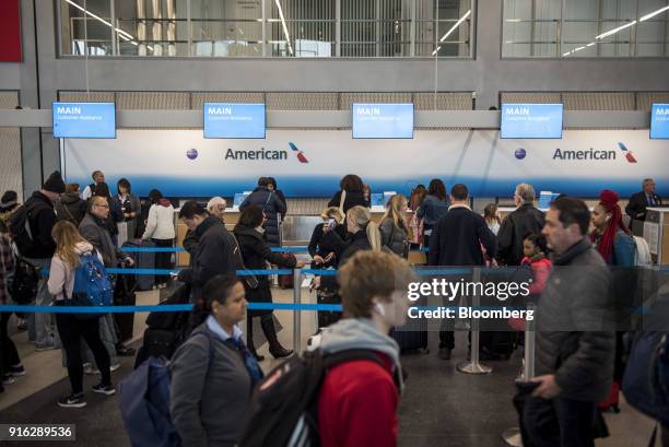 Travelers wait in line at the American Airlines Group customer assistance desk inside O'Hare International Airport during a snow storm in Chicago,...