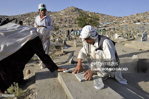 In this photo taken September 24 shows Afghans visiting the tomb of a relative at Sakhi Cemetery in Kabul where many victims of the civil war are...